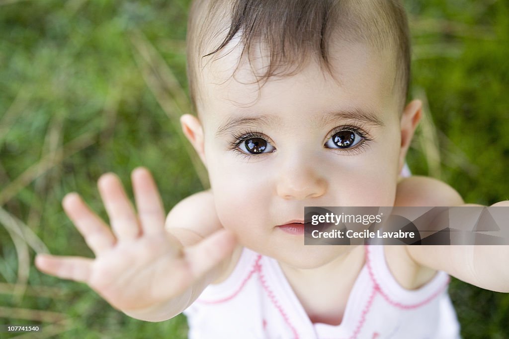 Portrait of a baby girl with arms raised