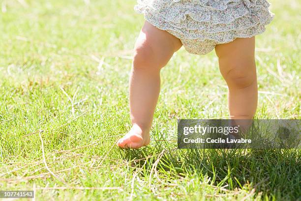 legs of baby girl walking - male feet stock-fotos und bilder