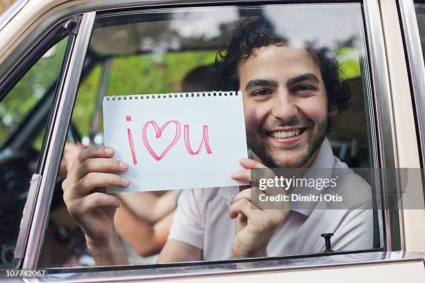 man in car holding sign saying 'i love you' - love you stockfoto's en -beelden