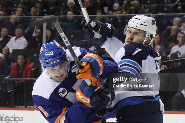 Ben Chiarot of the Winnipeg Jets checks Adam Pelech of the New York Islanders at the Barclays Center on December 04, 2018 in the Brooklyn borough of...