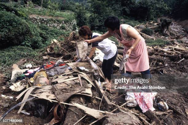 Residents pick up stuffs at a place their house used to stand after a landslide is seen triggered by Typhoon Bess hits across Japan on August 4, 1982...