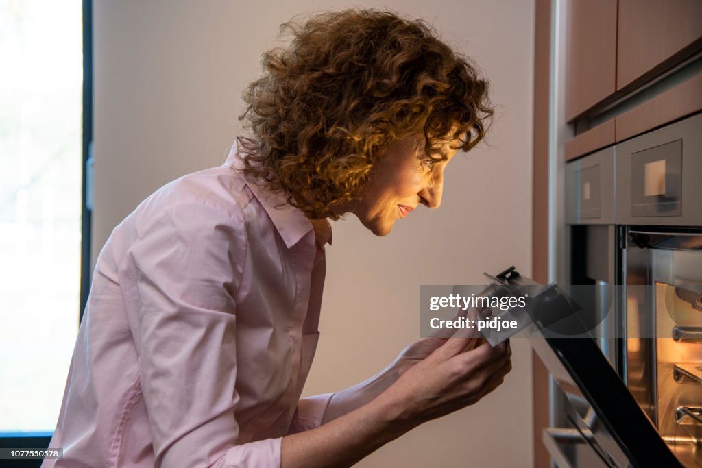 Side view of Woman checking food in the oven