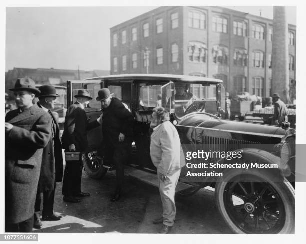 Charles Steinmetz waits as Thomas Edison exits a vehicle during Edison's visit to General Electric's Schenectady plant.