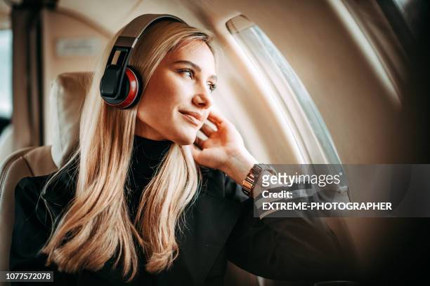 beautiful young woman listening to music through the headphones in a private jet - air travel stock pictures, royalty-free photos & images