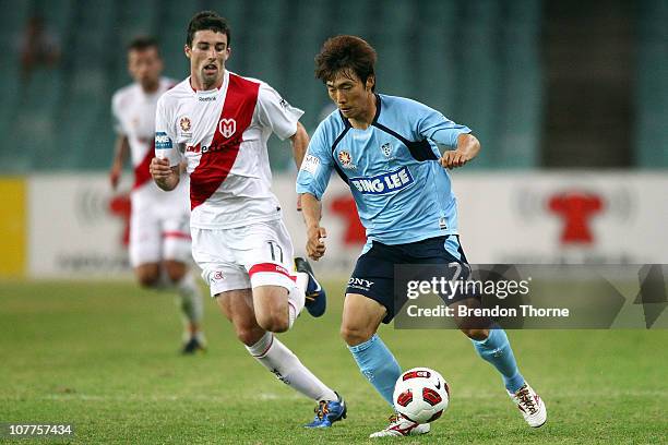 Sung-Hwan Byun of Sydney FC dribbles the ball while Jason Hoffman of the Heart gives chase during the round 20 A-League match between Sydney FC and...