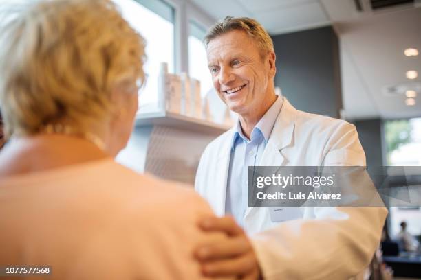 male chemist consoling customer at pharmacy - pharmacist and patient stock pictures, royalty-free photos & images