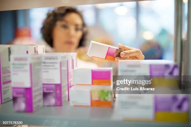 female pharmacist checking medicines on rack - arzneimittel stock-fotos und bilder