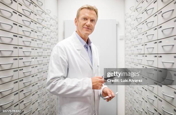 senior male pharmacist working at drug store - doctor lab coat imagens e fotografias de stock