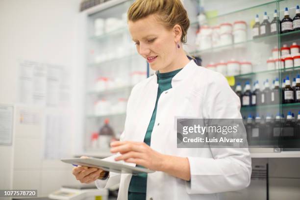 female pharmacist using digital tablet in medical lab - homöopathie stock-fotos und bilder