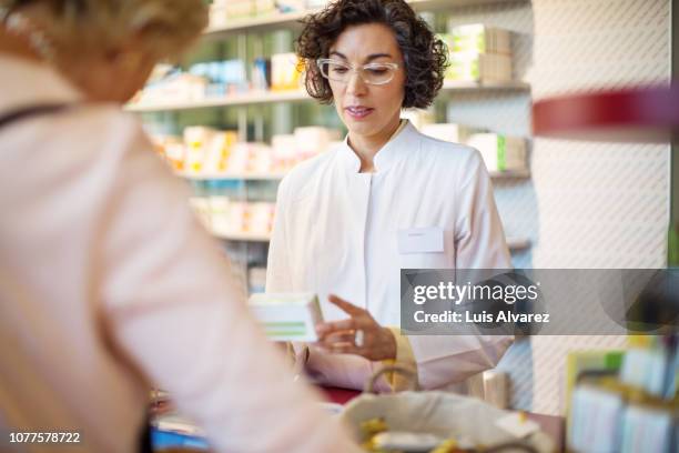 pharmacist assisting woman client at checkout counter at pharmacy - pharmacist explaining stock pictures, royalty-free photos & images