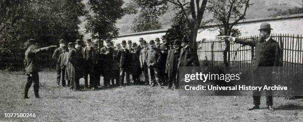 Two men set up a mock duel as onlookers watch. France 1902.