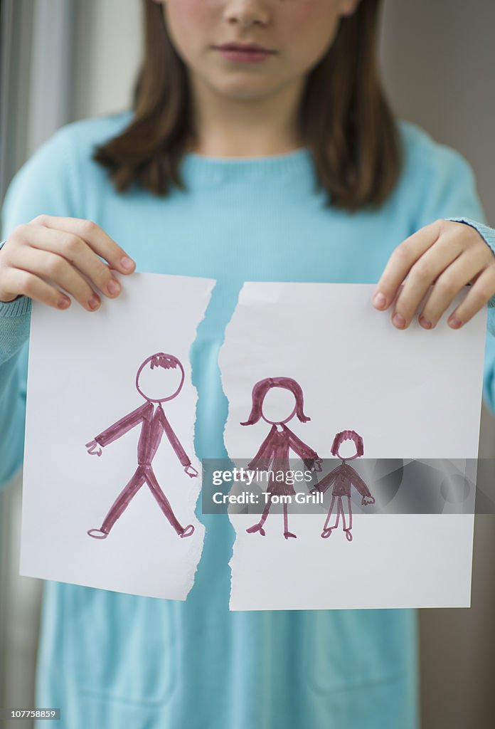 Girl holding drawing of split family