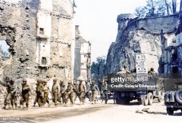 Operation Overlord Normandy, United States Army trucks and jeeps are driving through the ruins of Saint-Lo. July 1944. A group of American soldiers...