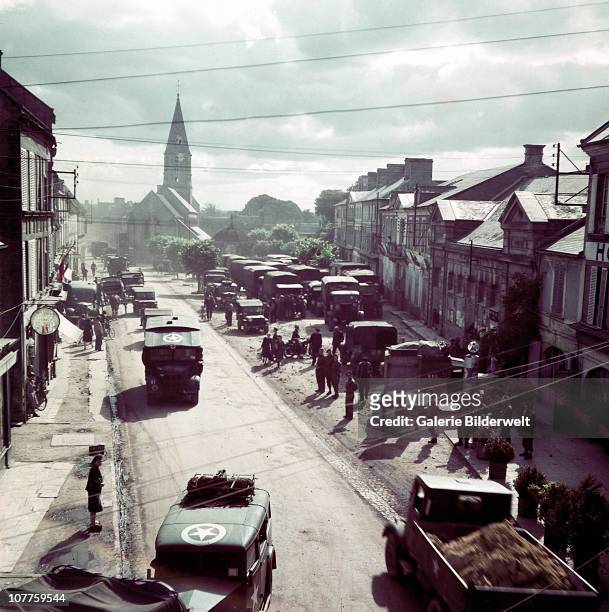 Operation Overlord Normandy, United States Army trucks, jeeps and other vehicles have entered a town in Normandy, France. June 1944. They are part of...