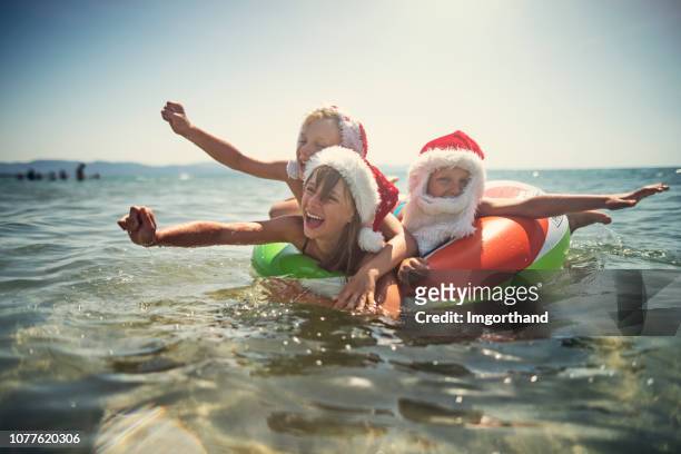 kinder spielen im meer auf schwimmring im sommer weihnachten - beach christmas stock-fotos und bilder