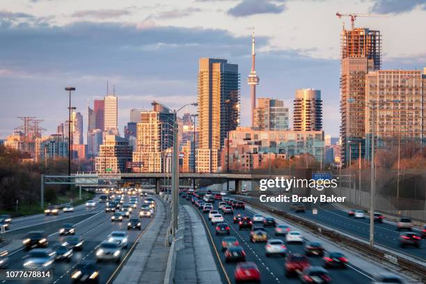 toronto city skyline at sunset set beyond commuter traffic filling roadway - toronto ontario canada fotografías e imágenes de stock