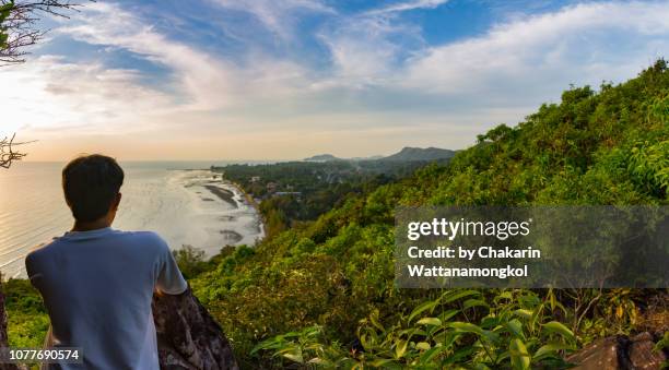 a man standing on the hill top looking at view of chao lao beach at time of sunset, chanthaburi. - chanthaburi sea fotografías e imágenes de stock