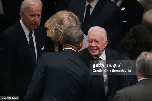Former presidents Barack Obama and Jimmy Carter greet one another during the state funeral for former President George H.W. Bush at the National...