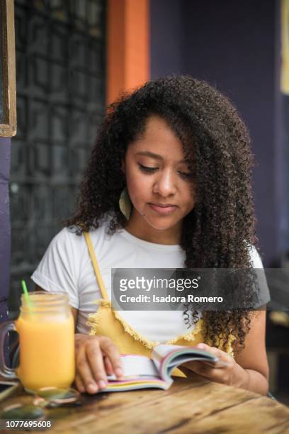 Latina woman in cafe drinking a juice and reading