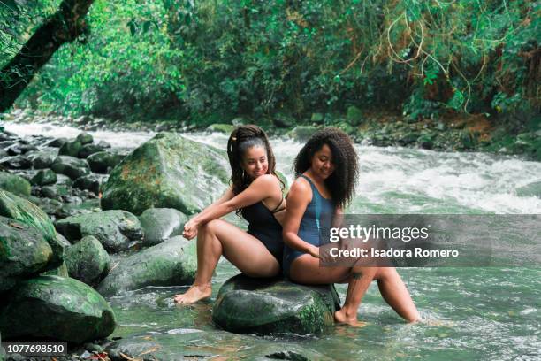 young woman sitting in a rock in the river - valle del cauca stock-fotos und bilder