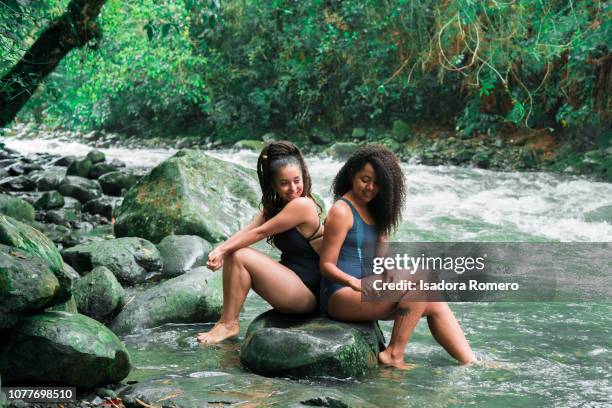 young woman sitting in a rock in the river - cali morales stock pictures, royalty-free photos & images