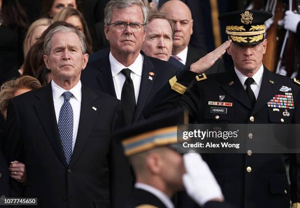 Former U.S. President George W. Bush, his brothers Jeb Bush and Neil Bush watch a joint service honor guard carry the casket of their father and...