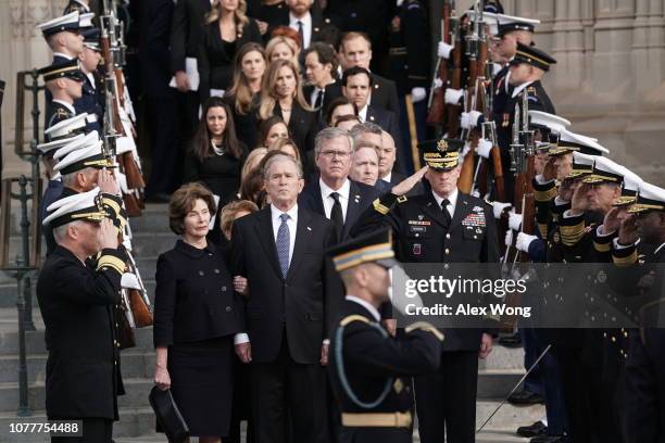 Former U.S. President George W. Bush, his wife Laura Bush, and his brothers Jeb Bush and Neil Bush watch a joint service honor guard carry the casket...
