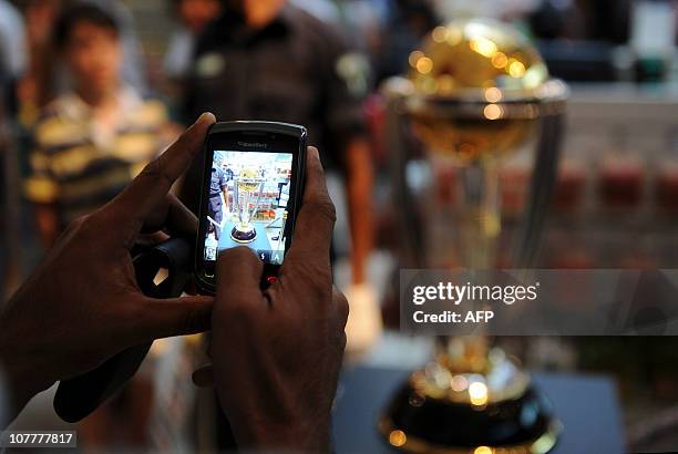 Sri Lankan shoppers takes a picture with a mobile phone of 2011 Cricket World Cup trophy on display at the Odel shopping mall in Colombo on December...