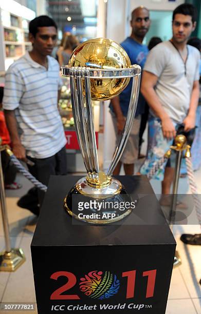 Sri Lankan shoppers walk past the 2011 ICC Cricket World Cup trophy on display at the Odel shopping mall in Colombo on December 24, 2010. The cup is...