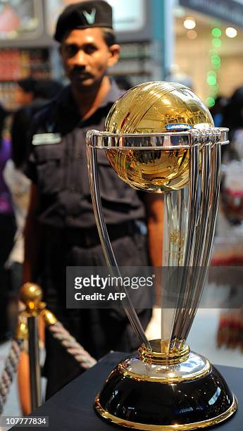 Sri Lankan guard looks on next to the 2011 ICC Cricket World Cup trophy on display at the Odel shopping mall in Colombo on December 24, 2010. The...