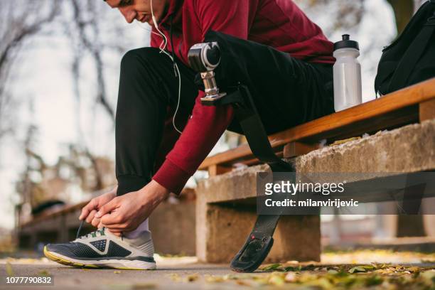 Man with prosthetic leg make preparation for running
