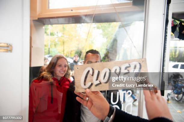 mixed couple waiting for a shop to open - bordje-met-openingstijden stockfoto's en -beelden