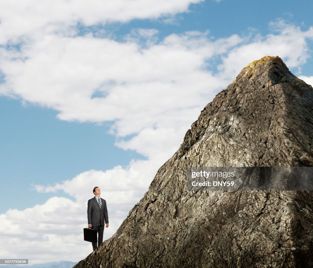 Empresario mirando para arriba en el pico de la montaña