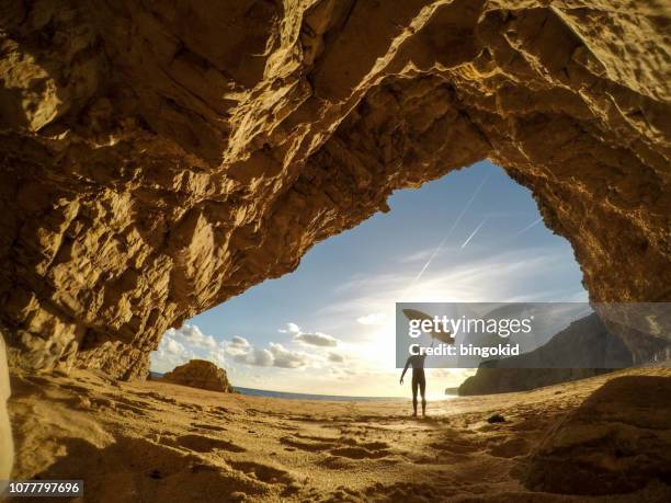 surfer holding a surfboard up into the sun - surf excel stock pictures, royalty-free photos & images