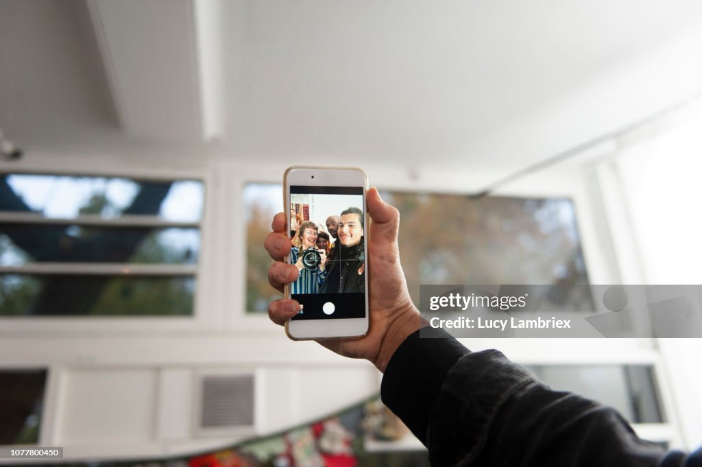 Young man taking group selfies at a creative pop up store