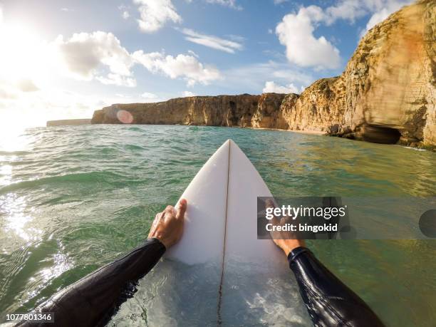 surfista che tiene una tavola da surf in acqua - prospettiva del fotografo foto e immagini stock