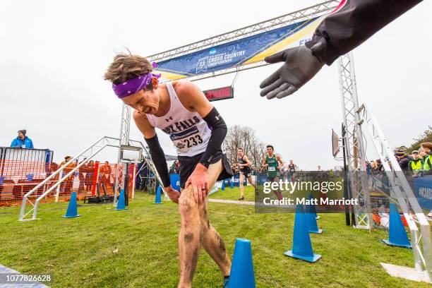 Exhausted runners cross the finish line and are assisted by volunteers during the Division II Men's Cross Country Championship held at Cooper's Lake...