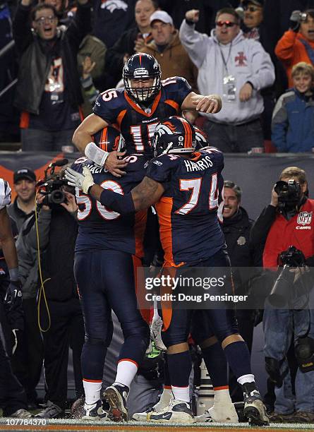 Quarterback Tim Tebow of the Denver Broncos jumps into the arms of his offensive linemen J.D. Walton and Ryan Harris after his game winning six yard...