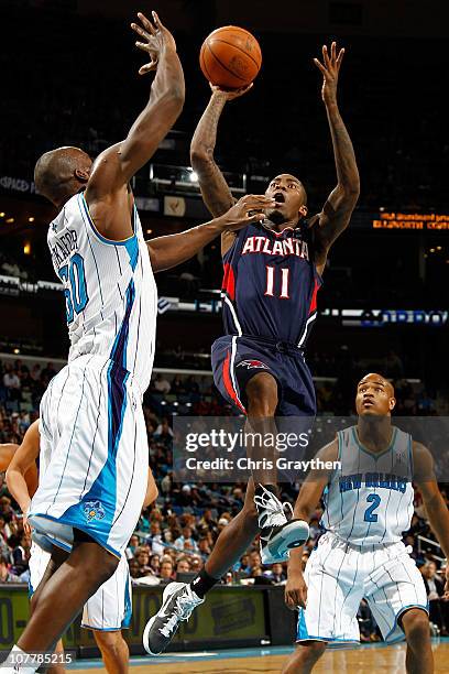 Jamal Crawford of the Atlanta Hawks shoots the ball over Emeka Okafor of the New Orleans Hornets at the New Orleans Arena on December 26, 2010 in New...