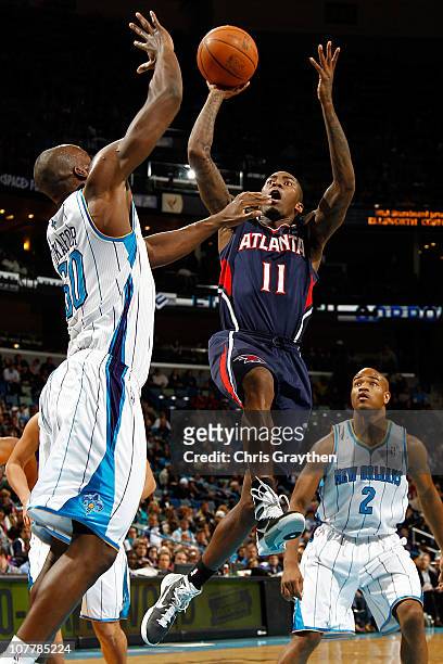 Jamal Crawford of the Atlanta Hawks shoots the ball over Emeka Okafor of the New Orleans Hornets at the New Orleans Arena on December 26, 2010 in New...