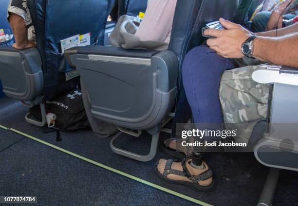 mann mit beinprothese ist eng in seinem sitz im flugzeug sitzen - aisle seat airline stock-fotos und bilder