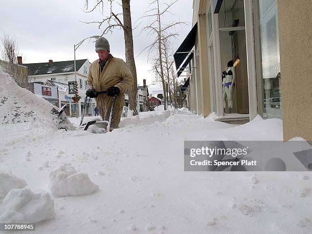 Town employee clears a sidewalk following a snow storm on December 27, 2010 in Westport, Connecticut. Much of the northeast of the United States is...