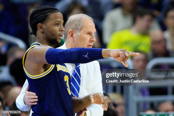 Zavier Simpson of the Michigan Wolverines discusses a play with Head coach John Beilein of the Michigan Wolverines in the game against the...