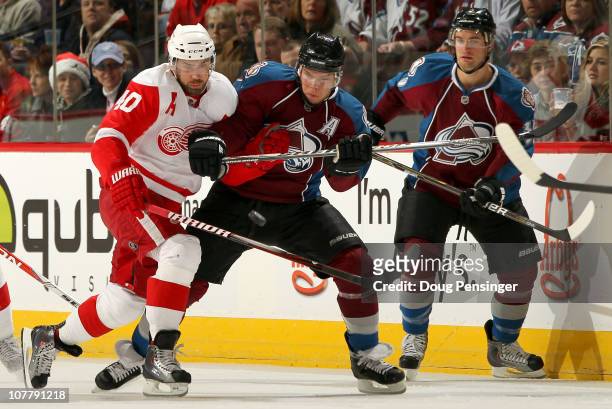 Henrik Zetterberg of the Detroit Red Wings and Paul Stastny of the Colorado Avalanche battle for the puck as TJ Galiardi of the Avalanche follows the...