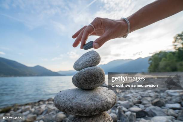 detail der person stapeln felsen am see - beach stone stock-fotos und bilder