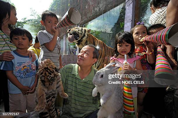 Zoo owner Manny Tangco holds up a rabbit and a tiger cub while surrounded by local children at the Malabon Zoo in Malabon, in northern Metro Manila...