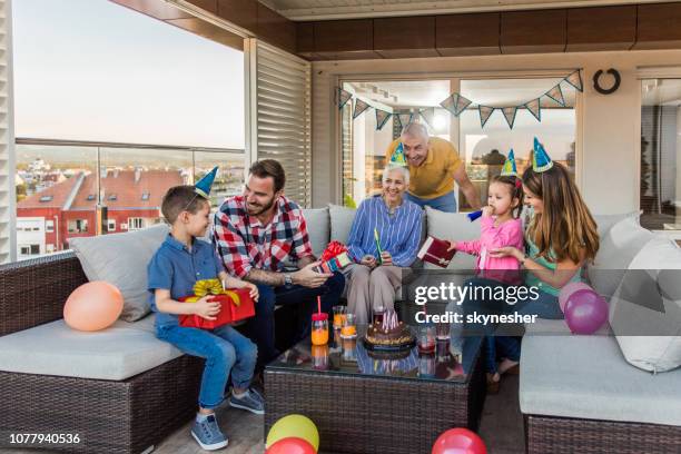 happy multi-generation family relaxing at penthouse terrace while having a birthday party. - penthouse girl stock pictures, royalty-free photos & images