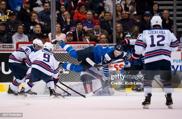 Rasmus Kupari of Finland goes flying through the crease and over goalie Cayden Primeau of the United States while trying to get a shot on net in Gold...