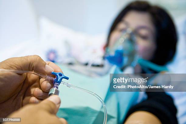 doctor adjusting patient's iv drip, cropped - iv drip womans hand fotografías e imágenes de stock