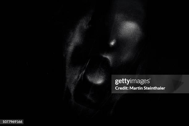 schreiendes gesicht hinter schwarzen latex stoff - latex stockfoto's en -beelden